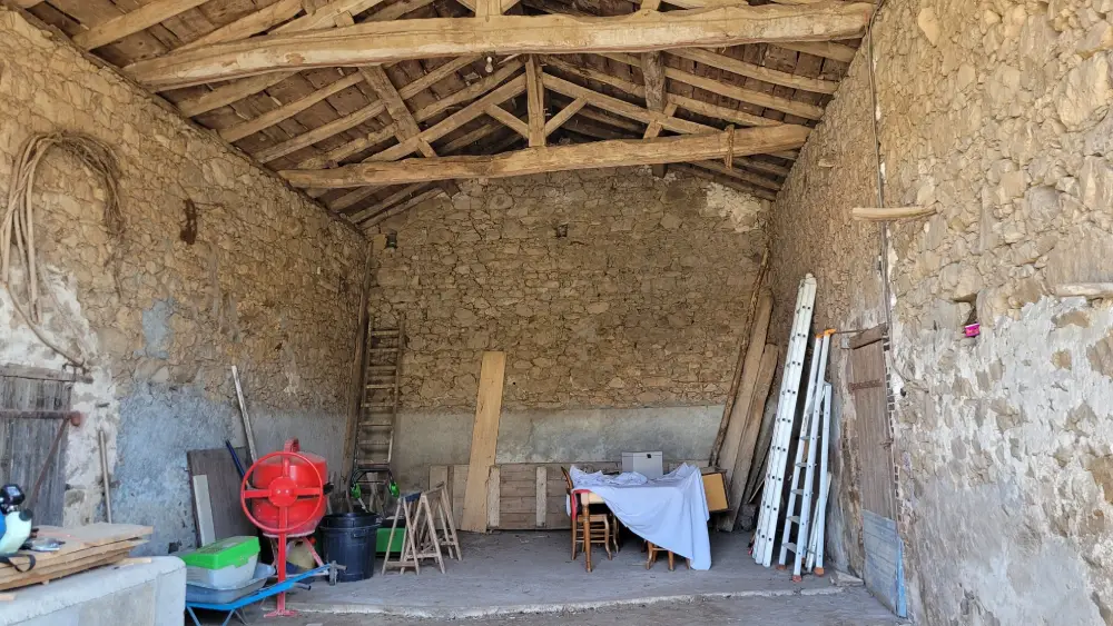 Intérieur d'une grange à rénover avec grande hauteur sous plafond et charpente apparente