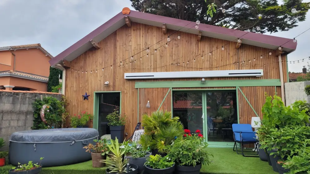 Rénovation de la façade avec bardage bois naturel pose vertical, couverture en tuiles avec large débord de toit et menuiseries en aluminium laqué vert pâle
