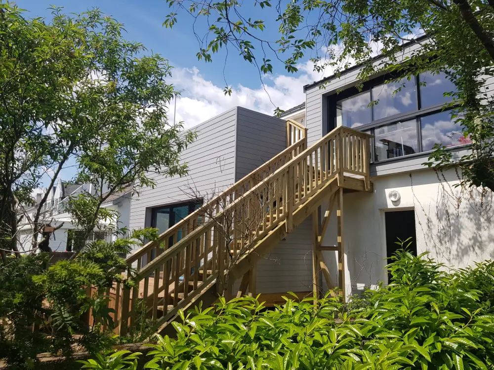 Extension en ossature bois avec escalier en bois massif pour atteindre la terrasse sur le toit de l'extension